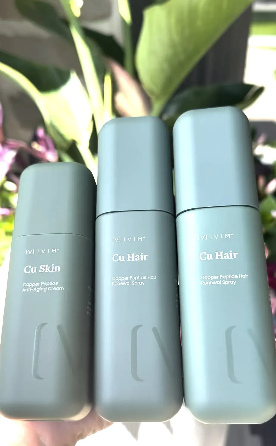 Ivím Cu Skin and Cu Hair bottles against greenery